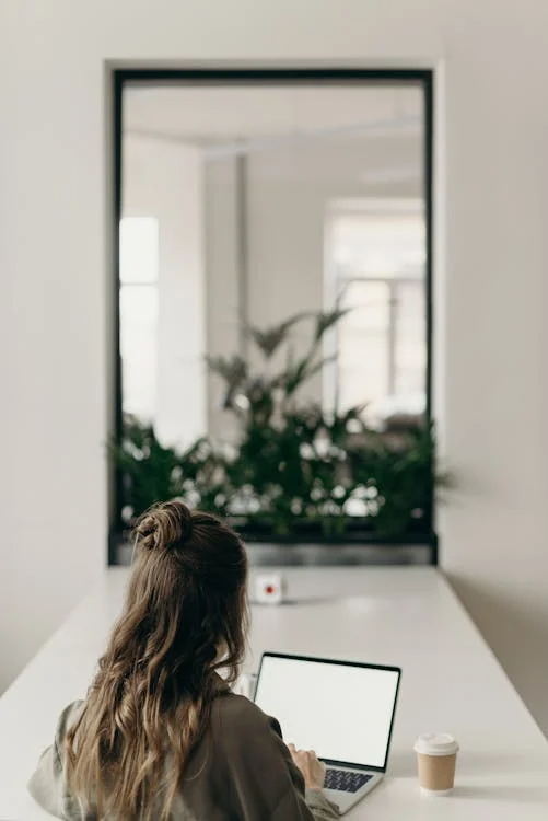 Woman working on a laptop with a cup of coffee nearby, setting up an email campaign